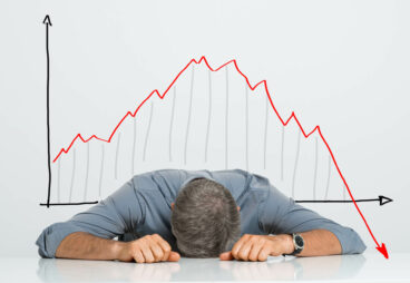 Depressed Businessman Leaning His Head Below a Bad Stock Market Chart